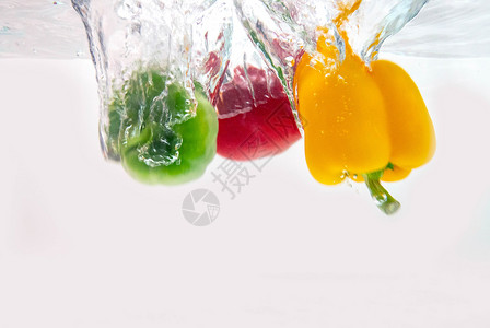 各种甜辣椒被扔入清澈的水中背景图片