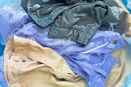 湿衣服Trouses 浸泡在粉末洗涤水溶解中搪瓷棉布蓝色黑发身体篮子机器衣服垫圈气泡背景