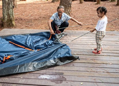 亚洲祖父和女女童正在帮助在露营地点搭建帐篷 儿童环境高清图片素材