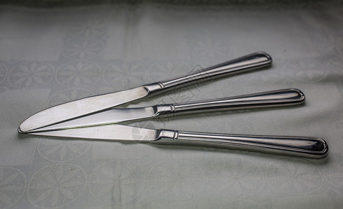 耐候钢桌上的不锈银钢餐刀勺子工具反思金属不锈钢刀具背景
