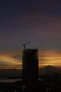 日落时建筑工地橙子工业城市起重机工程商业天空太阳工作建筑学背景图片