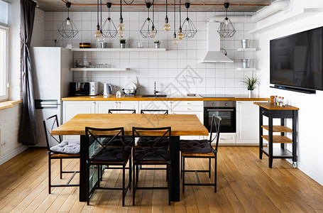 现代斯堪的纳维亚式厨房室内设计 大木桌和椅子与浅色木地板 明亮的白色墙壁和带电视 电器和悬挂灯泡的家具阁楼古董饭厅橡木富裕烤箱架背景图片
