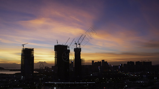 日落时建筑工地起重机橙子天空太阳工作商业工业建筑学工程城市背景图片