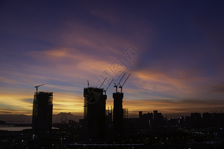 日落时建筑工地商业工程城市起重机工业太阳天空橙子建筑学工作背景图片
