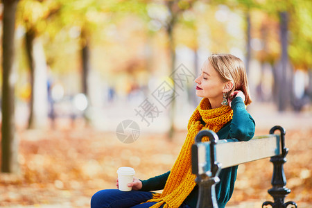 穿着黄围巾的快乐少女 在秋天公园散步衣服女孩森林成人树叶街道长椅理发阳光公园背景