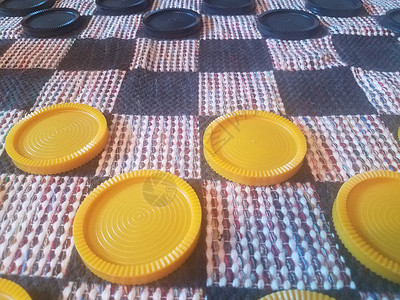 织物检查板上的黑色和黄色棋盘光盘游戏跳棋纺织品塑料圆圈娱乐背景图片