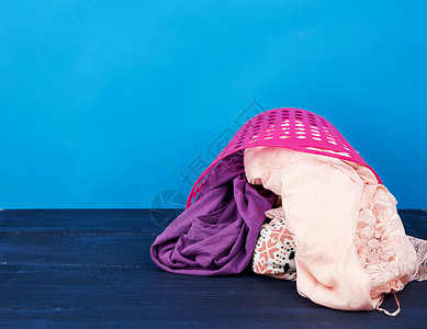 粉红色塑料篮 装满了衣服和蓝色背面的衬布衬衫粉色浴室纺织品琐事柳条家庭织物棉布洗衣店背景图片