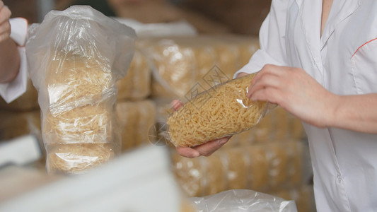 工人们从生产线上包装一个意大利面面粉制造厂的粗通心粉工人营养食物设备烹饪工厂输送带制造加工工业技术高清图片素材