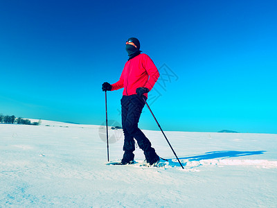 有雪鞋的观光客在雪地漂流中行走 阳光寒冷的天气鞋套护颈场景远足手套衬套装备荒野晴天漂移爬坡道高清图片素材