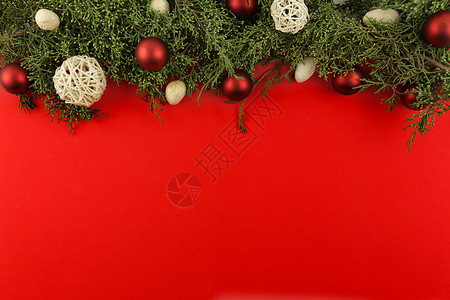 红白装饰球平铺红色的圣诞节复制空间 上面有松树枝和红白圣诞面包圈背景