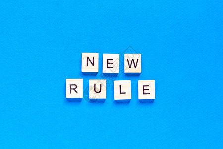 新规则是用木制字母写在蓝色背景上的 新概念 商业 法律 规则 更新 顶视图 平面布局背景图片