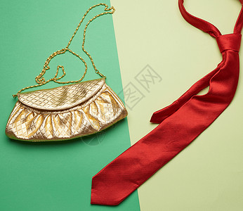 金色时装手袋在链条上 红丝领带在绿色衣服丝绸纺织品脖子领结女性织物商业离合器条纹背景图片