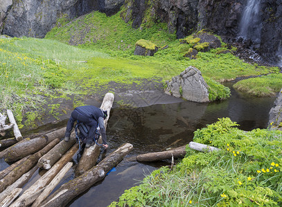 男子徒步者站在木头上 取干净的水 灌满背景图片