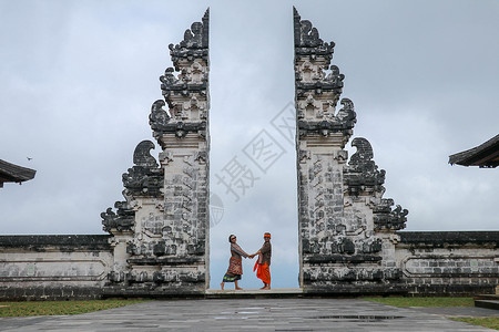 幸福的一对年轻夫妇住在天堂的庙门上 相互牵手 完美的蜜月概念 印度尼西亚巴厘岛寺庙游客建筑学女士旅游精神宗教冒险男人历史性天空老的高清图片素材