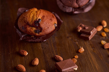 在一张木桌上的巧克力玛芬用巧克力和塔塔里尼清洁坚果海绵可可产品蛋糕盘子杏仁木板葡萄干背景图片