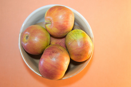红黄夏季苹果 在粉红色背景特端视图的浅碗中背景图片