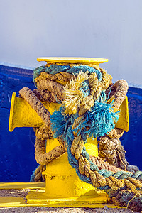 带锚系线的柱状体晴天圆圈海洋航海绳索黄色阴影码头船运港口背景图片