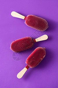 紫罗兰背景的草莓冰棒粉色冰淇淋白色水果巧克力小吃食物红色奶油棒冰背景图片