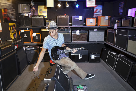 年轻男性客户用电吉他插上扬声器高清图片