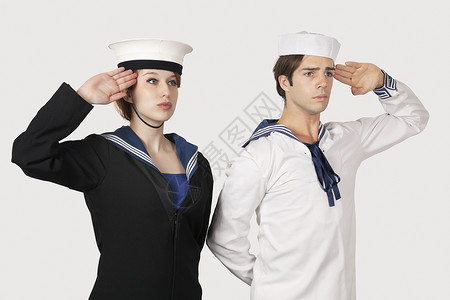 海军敬礼穿水手制服的男女青年 在灰色背景下敬礼背景