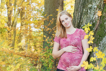 年轻怀孕妇女怀着孕期的肚子家庭生活生育力公园微笑女性喜悦母性阳光树木成人高清图片素材