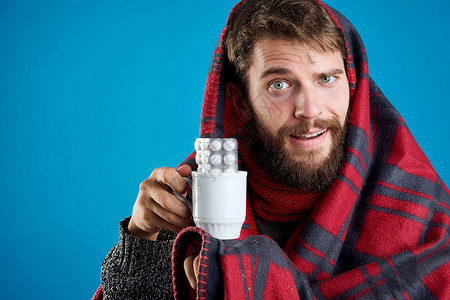 男人在蓝底健康药物和温暖衣物上吃药丸维生素疼痛鼻子疾病药片围巾药品胶囊蓝色流感背景图片