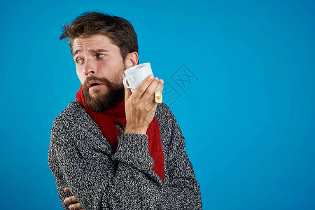 男人在蓝底健康药物和温暖衣物上吃药丸疼痛药品药片围巾感染胶囊流感组织疾病蓝色背景图片