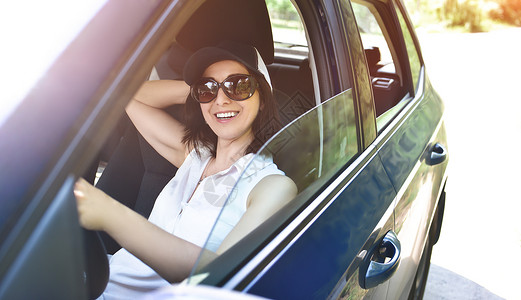 穿着帽子和墨镜的美丽成年快乐女子 在夏日驾驶她的汽车享受高清图片素材