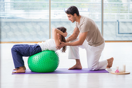 瑜伽瑞士球个人教练用稳定球帮助体操中的女子娱乐有氧运动健身房健身健康男人讲师瑜伽治疗重量背景