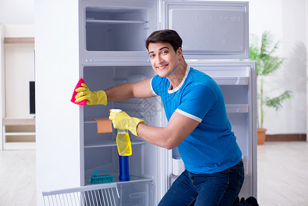 微笑的清洁工在卫生概念中男人清洁冰箱器具微笑管家家政架子灰尘清洁工家务承包商海绵背景