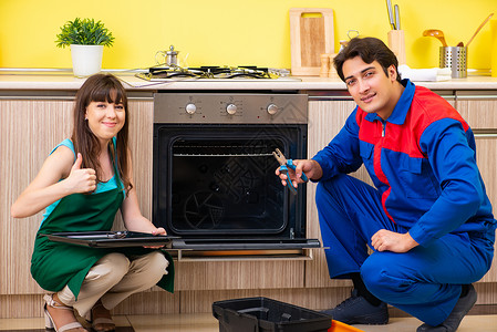 厨房有女承包商 在厨房讨论修理家具男人维修客户烤箱电工机械炊具顾客器具操作说明高清图片素材