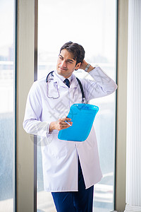 年轻英俊的医生站在窗边助手外科职业药品治疗临床男人实验室医院记录外套高清图片素材