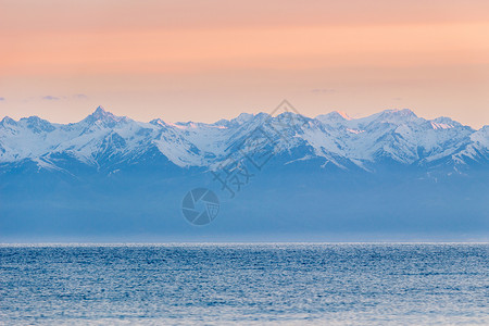 伊塞克湖湖 雪峰山和清晨粉红色天空高清图片