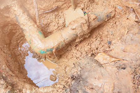 在路边候车修理时 在水运动下打孔中断的管子土壤弯头劳动下水道管道服务工作地面挖掘机空腔工人高清图片素材