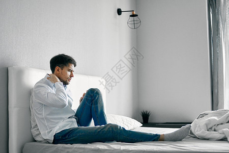 一个男人坐在床上 忧郁不满意的孤独后悔高清图片素材