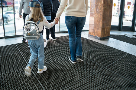 母亲用手牵着孩子走 背着背包在地上入户门高清图片素材