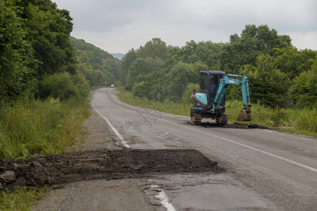 2016 年夏季  俄罗斯滨海边疆区  修复坏路 工人们在俄罗斯的森林里铺设了一条糟糕的道路运输滚筒机器活动工作街道蒸汽铺路施工修理高清图片素材