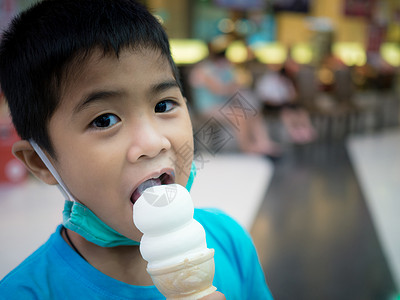 一个男孩在商场里吃冰淇淋 而背景模糊小男孩食物快乐儿子幸福甜点派对衬衫乐趣家庭嘴唇高清图片素材