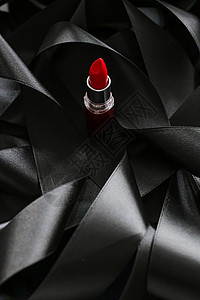 黑色丝绸背景的红口红 奢华化妆和美容女士光泽度魅力皮革化妆品静物红色背景图片