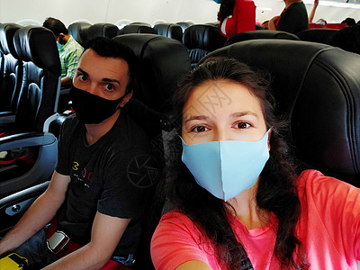 机舱内 一对戴着口罩的旅客 根据冠状病毒大流行的新规则飞行背景图片
