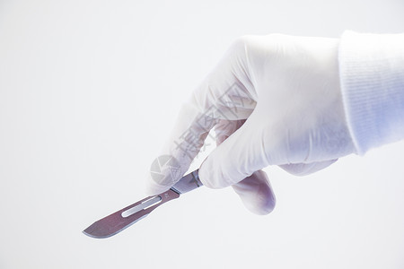 手刀手术刀握在白色背景上 工作室拍摄 手术设备 外科手术程序解剖学治疗医生手术台金属乐器采摘实验室手套刀刃背景