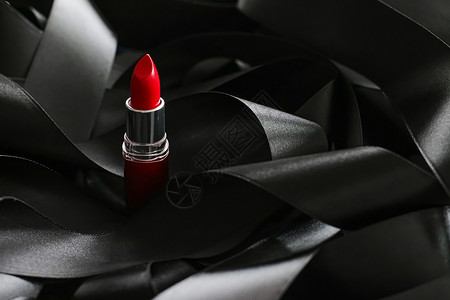 黑色丝绸背景的红口红 奢华化妆和美容光泽度化妆品静物红色魅力女士皮革背景图片