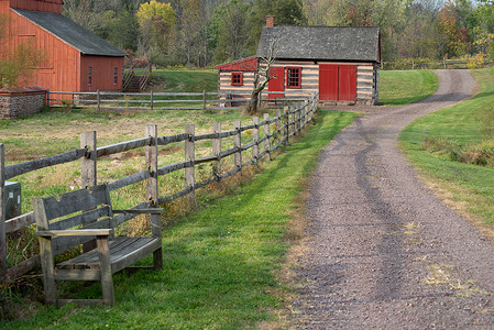 碎石路经过一个空的长凳 红色谷仓和木屋高清图片