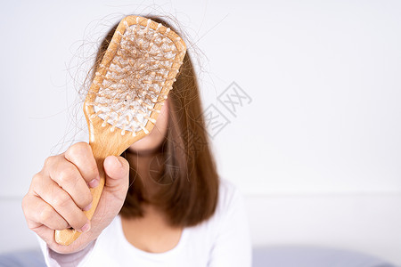 毛发掉落问题 紧身手握梳子和理发问题 保健医疗或日常生活概念秃顶头发化疗卫生恢复者女性护理脱发女士治疗背景图片