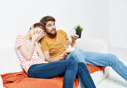 男人和女人在室内看有爆米花的电影 在锅里放花沙发微笑幸福女朋友娱乐房间拥抱浪漫房子男人女性高清图片素材