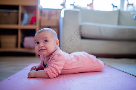 小贝鲁表情微笑的女婴躺在粉红鲁上婴儿孩子内饰育儿长椅俯卧姐妹童年窗户乐趣背景