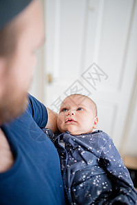 蓝一西的女婴在被抱着的时候 欣喜地仰慕她的父亲背景图片