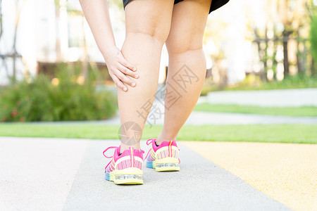 女性胖脚步运动员腿部受伤和疼痛 手抓着痛苦的腿在公园里跑来跑去跑步赛跑者训练小牛疾病肌肉十字形慢跑者膝盖按摩背景图片