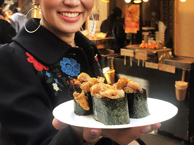 观光女游客展示牛肉寿司 最流行的美味食品店铺旅行蔬菜街道扇贝烹饪盘子海洋女士市场背景图片