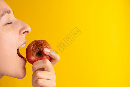 苹果虫子女孩咬了一只烂苹果 黄背上有虫子 过期的产品 垃圾食品厌恶牙齿老化食物皮肤腐烂水果女士危险模具背景